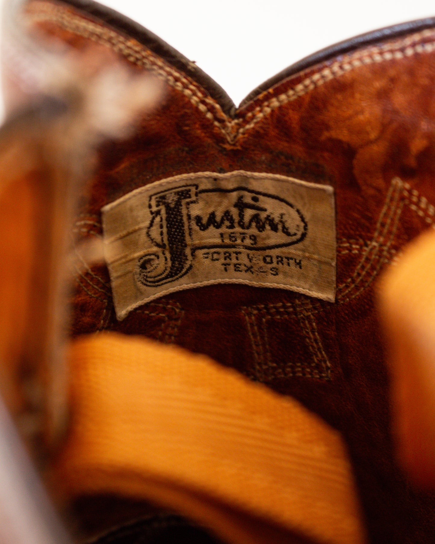 Close-up of a brown leather boot with 'Justin' branding on a white background