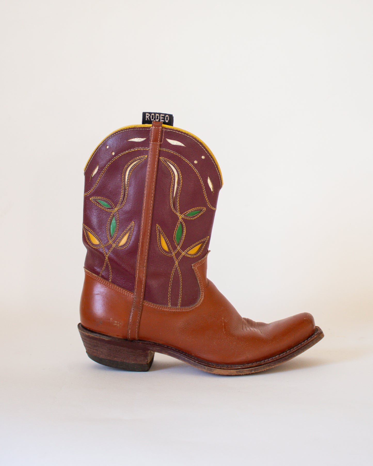 Brown cowboy boot with decorative patterns on a white background