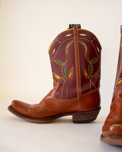 Brown cowboy boot with intricate designs on a white background
