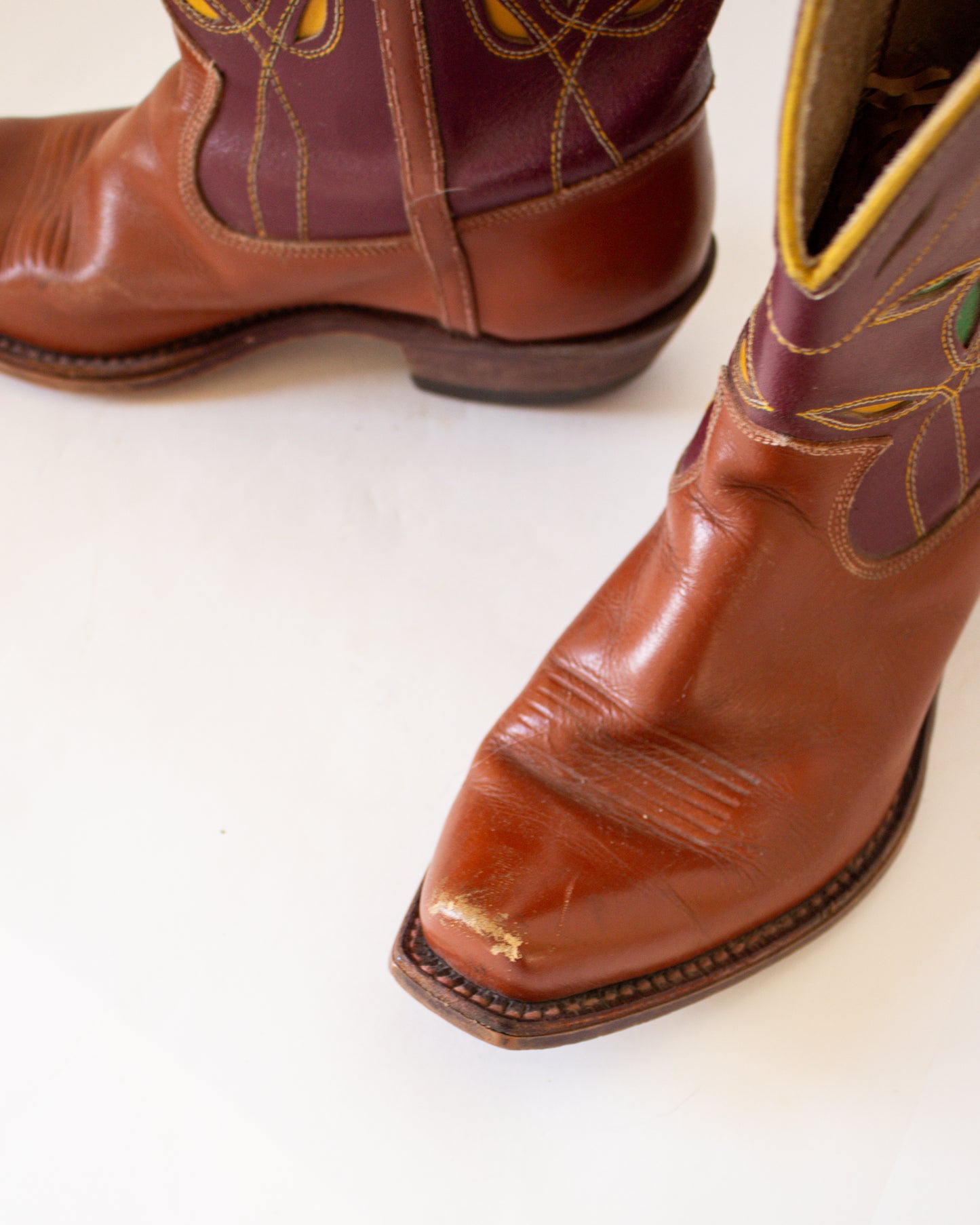 Brown leather cowboy boots with floral embroidery on a white background