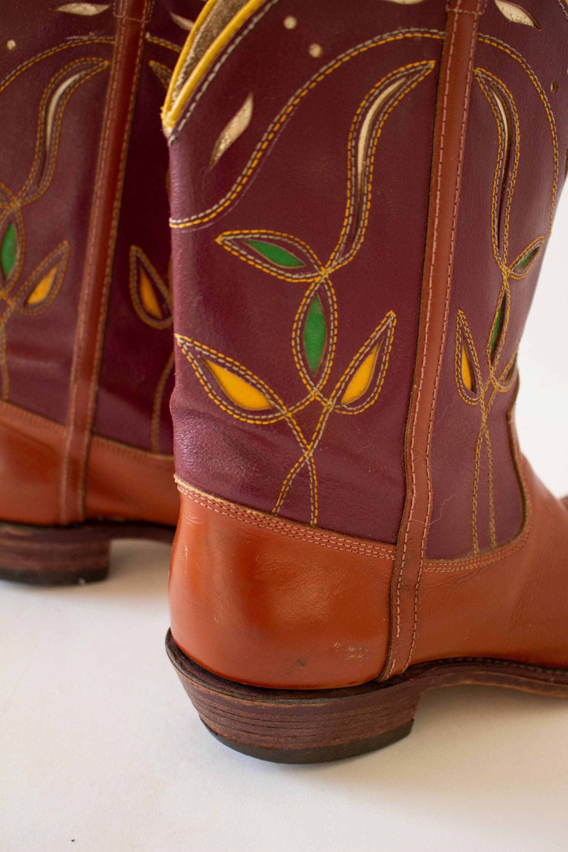 Close-up of a pair of brown leather boots with decorative stitching on a white background