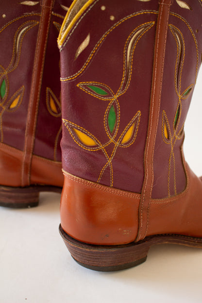 Close-up of a pair of brown leather boots with decorative stitching on a white background