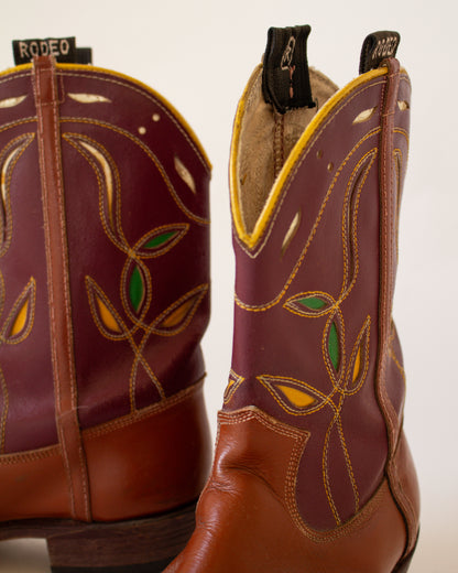 Pair of brown cowboy boots with decorative patterns on a white background