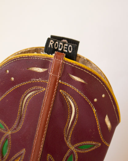 Close-up of a brown leather boot with decorative stitching and 'Rodeo' label on a white background