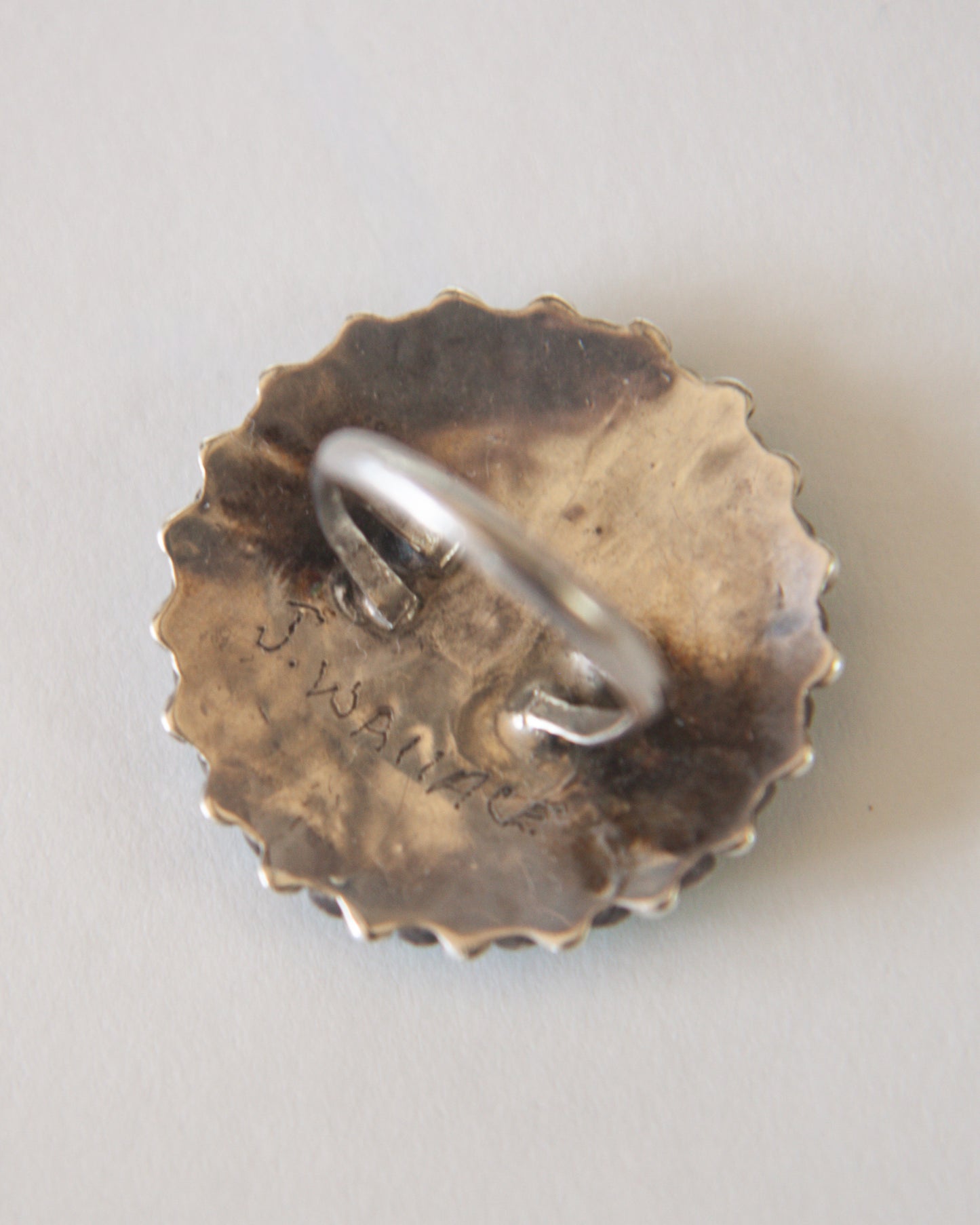 Silver ring on a textured bronze base with engraved text on a light gray background