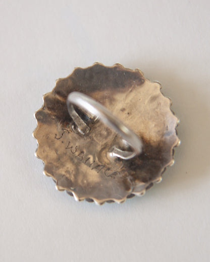 Silver ring on a textured bronze base with engraved text on a light gray background