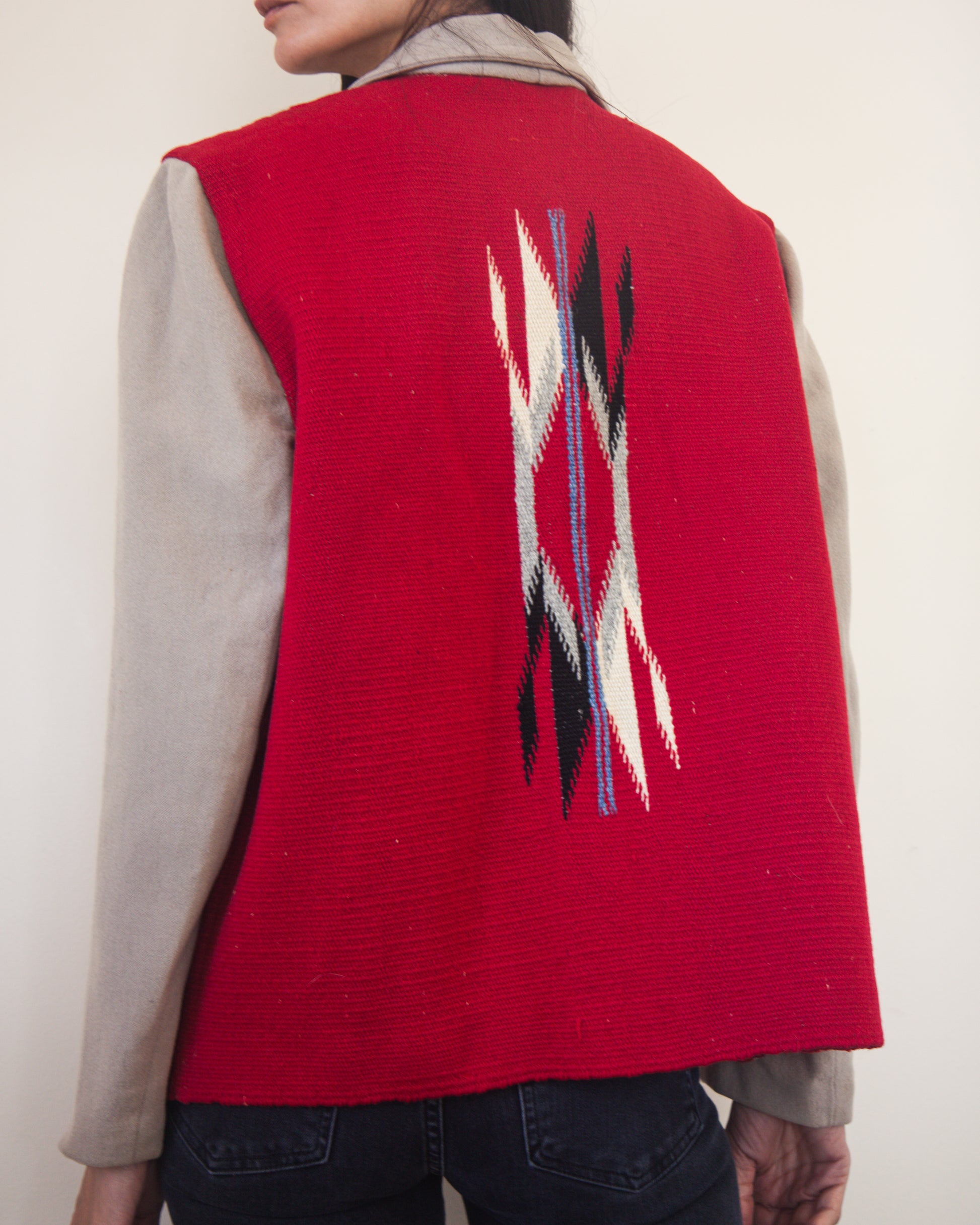 Red jacket with a geometric pattern on the back, worn by a person against a plain background