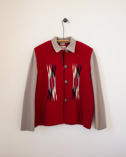 Red jacket with geometric patterns on a hanger against a white wall