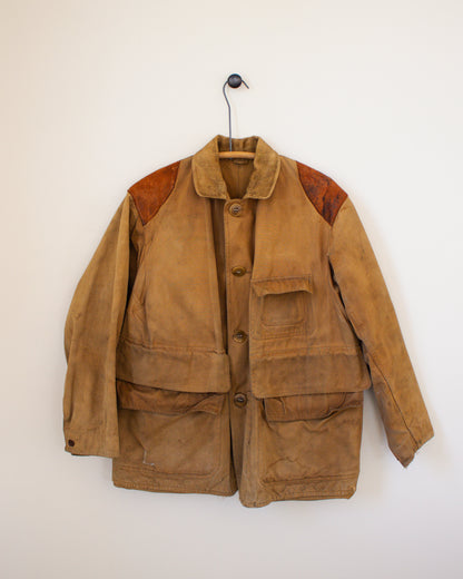 Brown jacket with leather patches on a hanger against a white wall