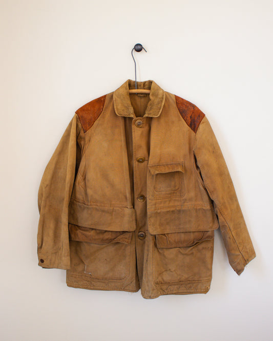 Brown jacket with leather patches on a hanger against a white wall