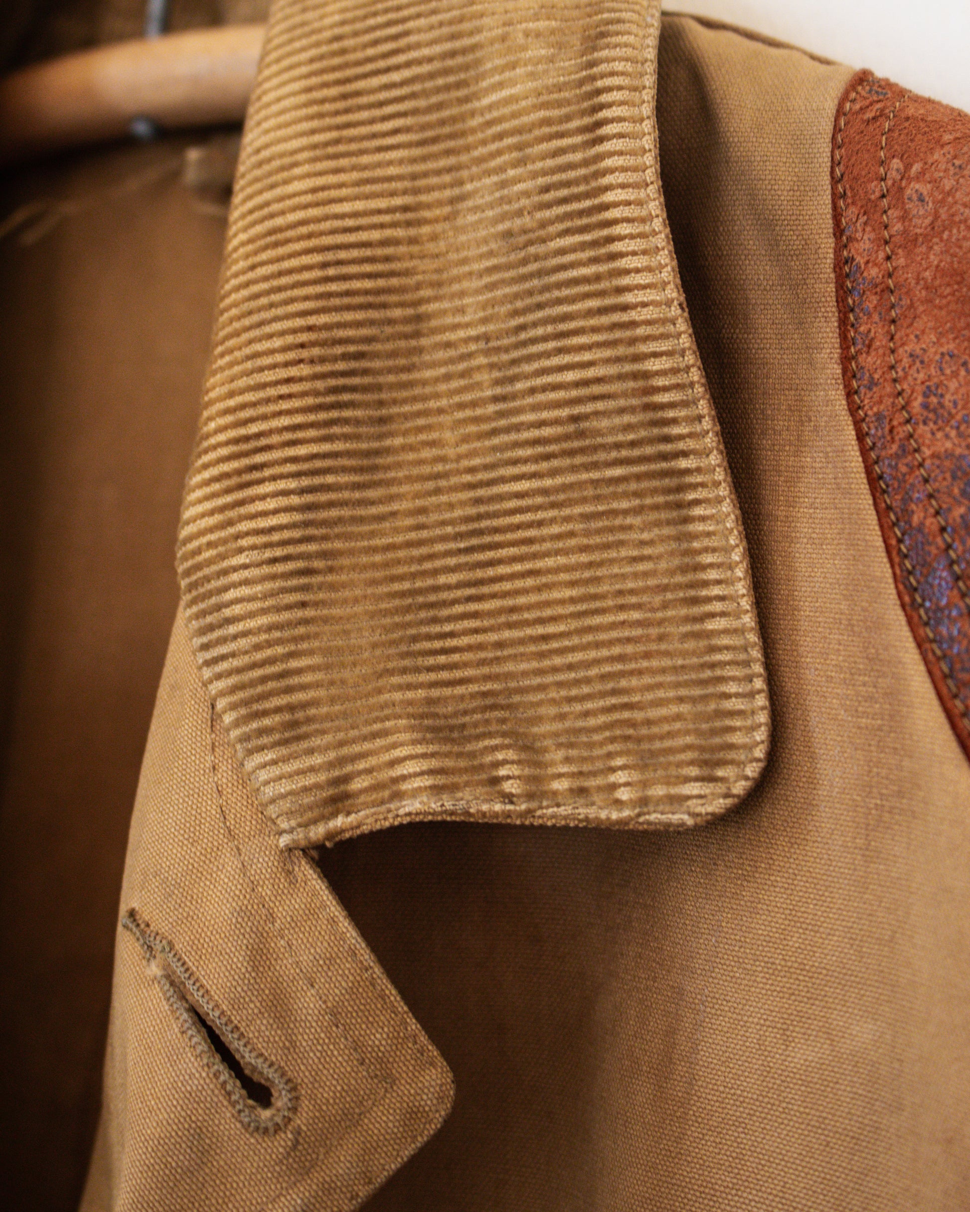 Close-up of a brown jacket with corduroy collar and leather patch on sleeve