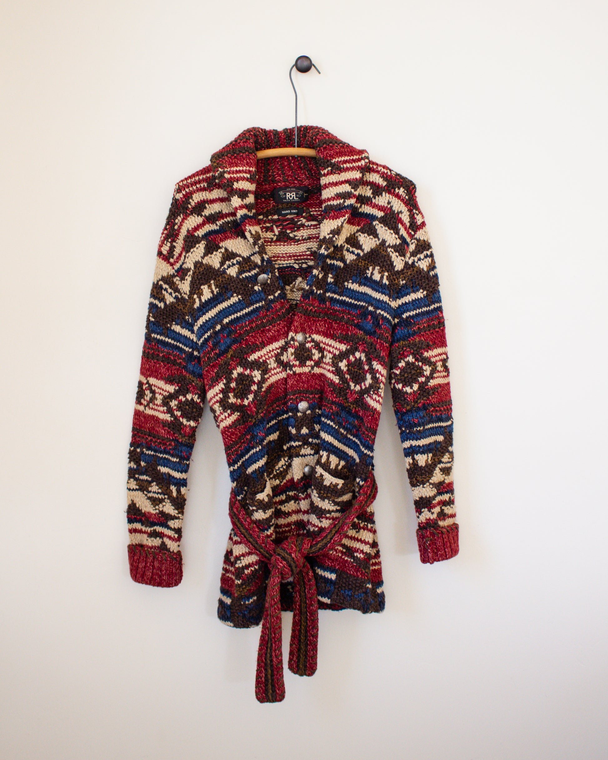 Colorful patterned cardigan on a hanger against a white background