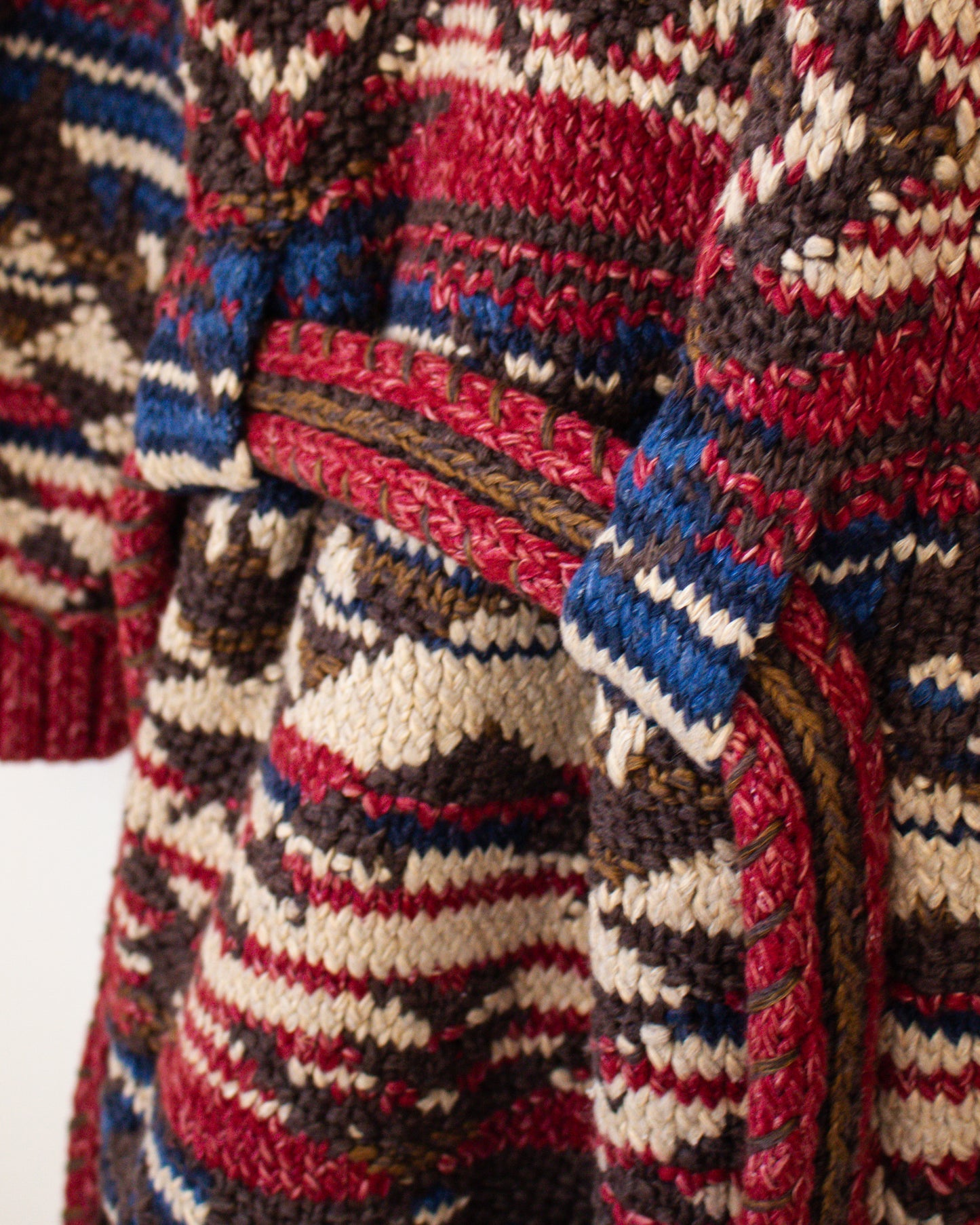 Close-up of a multicolored knitted fabric with red, blue, brown, and beige patterns.