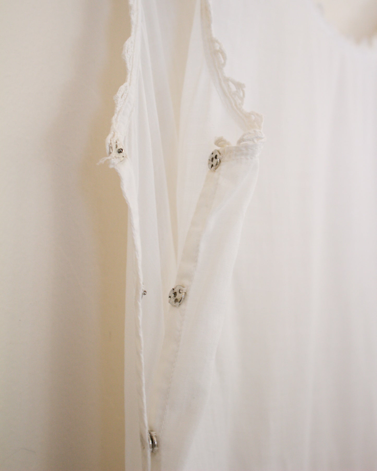 Close-up of a white lace garment with floral details on a plain background
