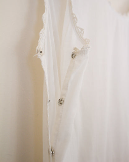 Close-up of a white lace garment with floral details on a plain background