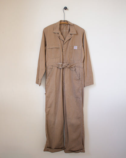 Brown coverall on a hanger against a white wall