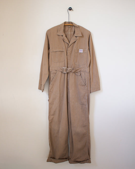 Brown coverall on a hanger against a white wall