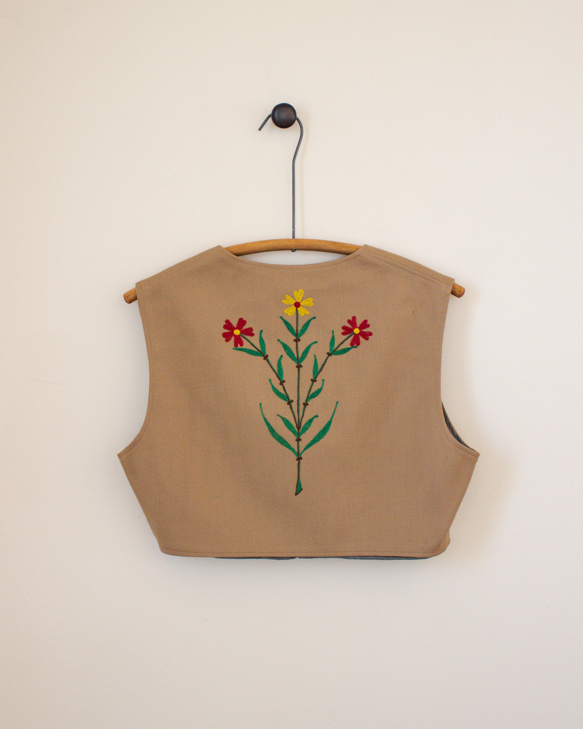 Beige sleeveless vest with floral embroidery on a beige background