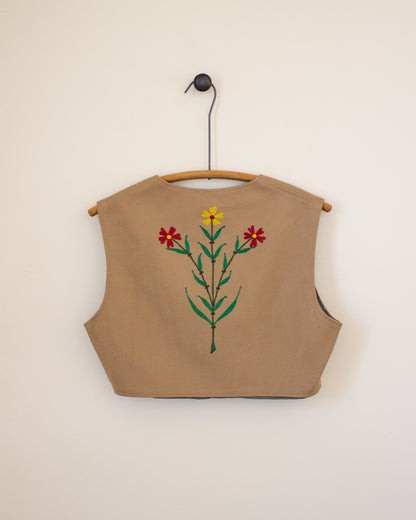 Beige sleeveless vest with floral embroidery on a beige background