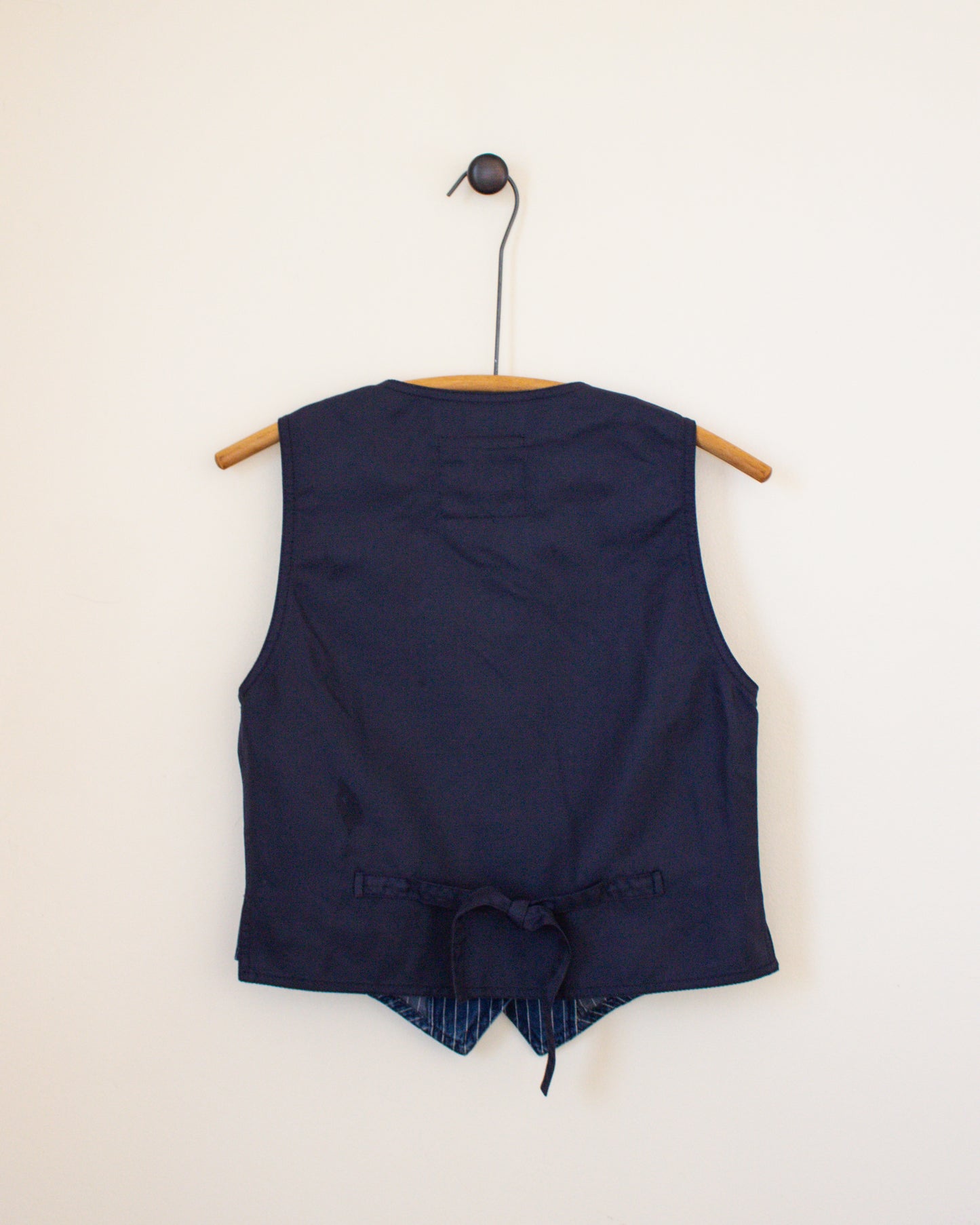 Navy blue sleeveless top with a tie detail on a beige background