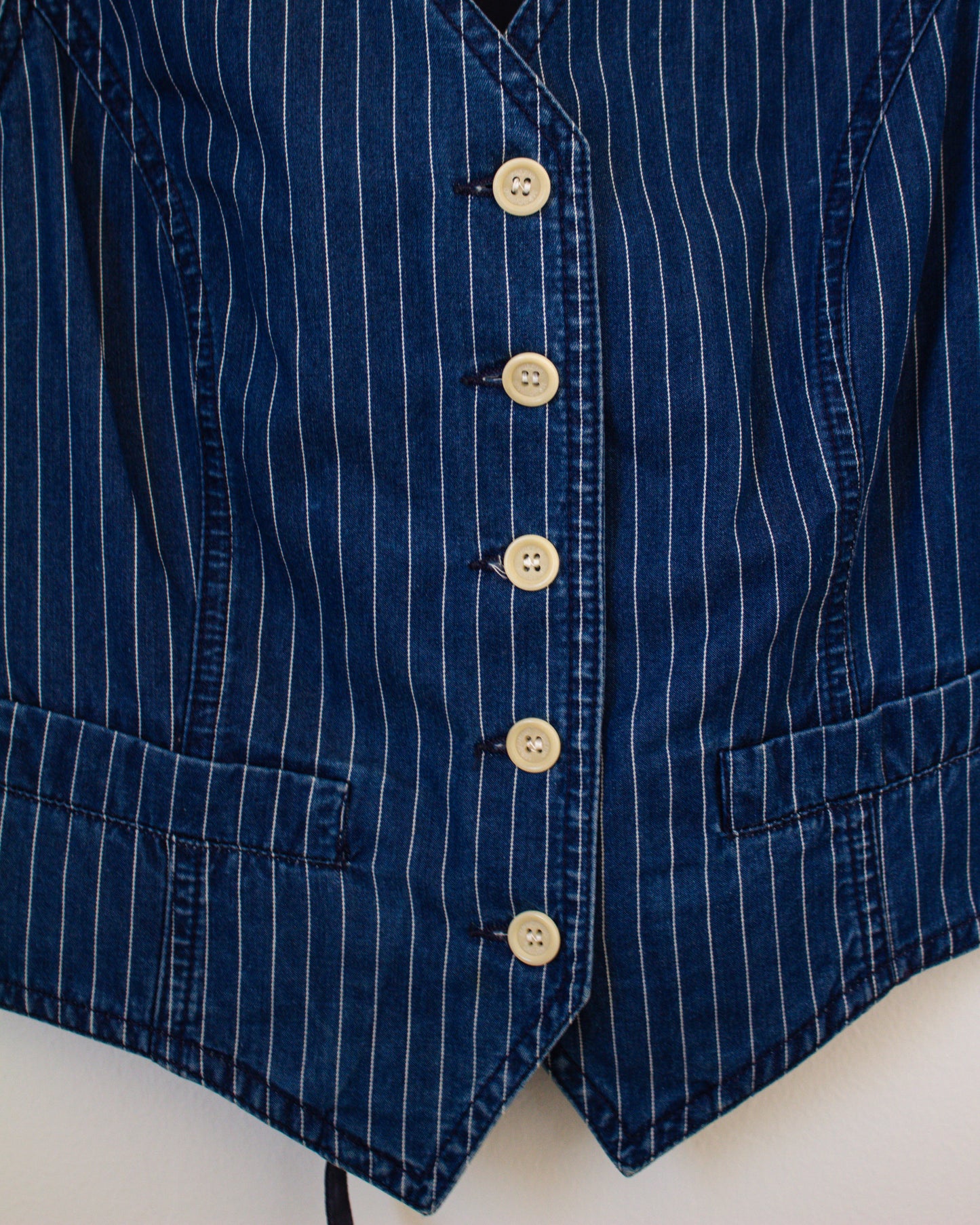 Close-up of a blue pinstripe vest with white buttons on a white background