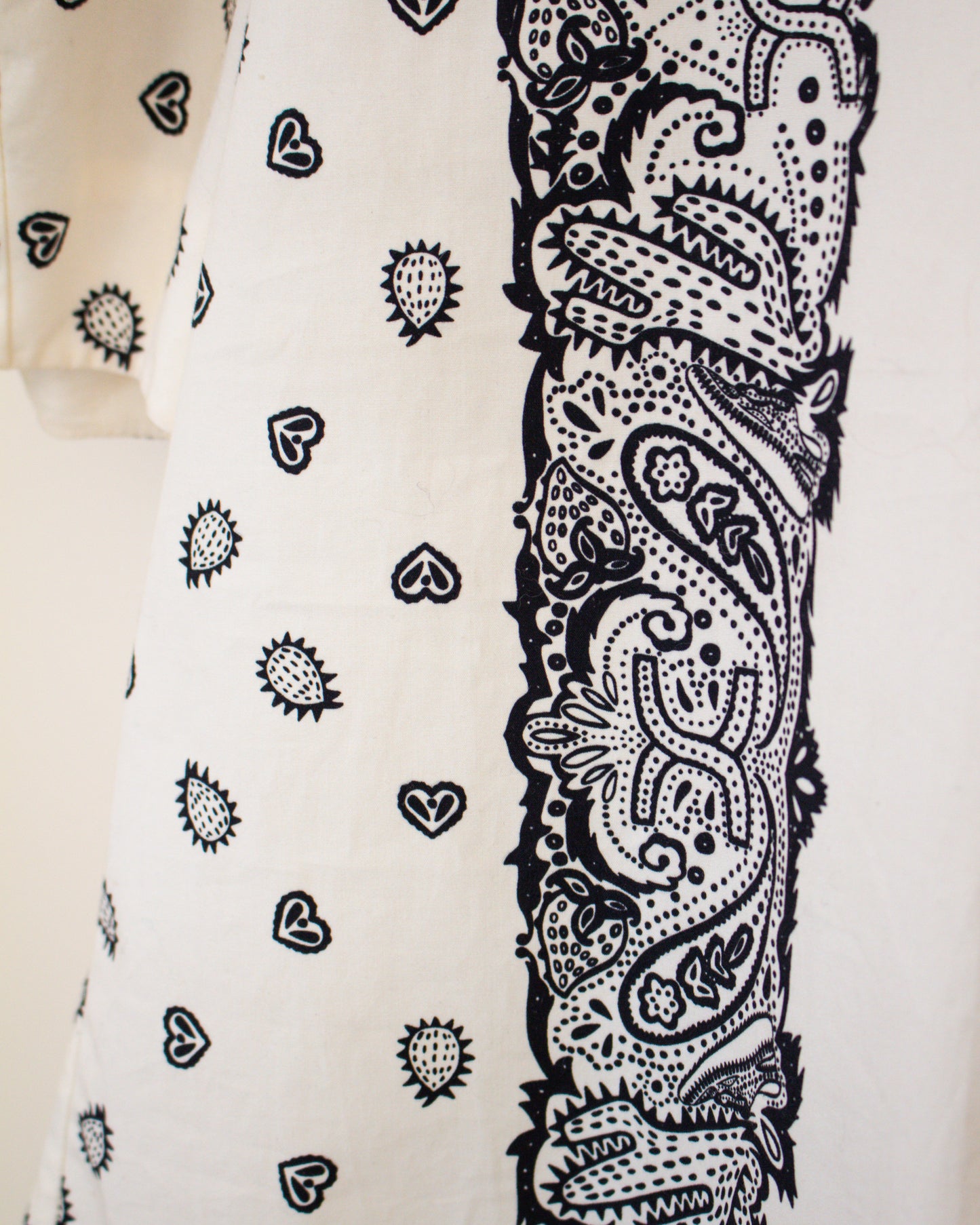 Close-up of a white fabric with black bandana and heart patterns.