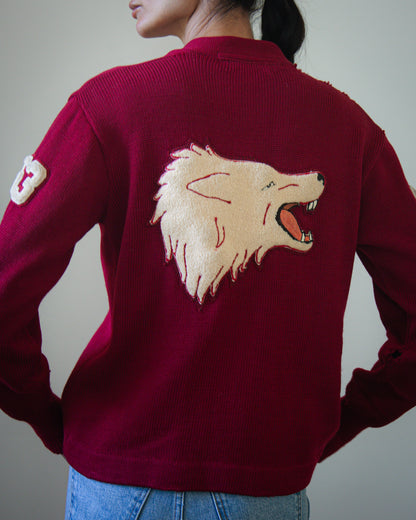 A person wearing a burgundy ribbed knit sweater, shown from the back. The sweater features a large beige embroidered wolf head on the back.