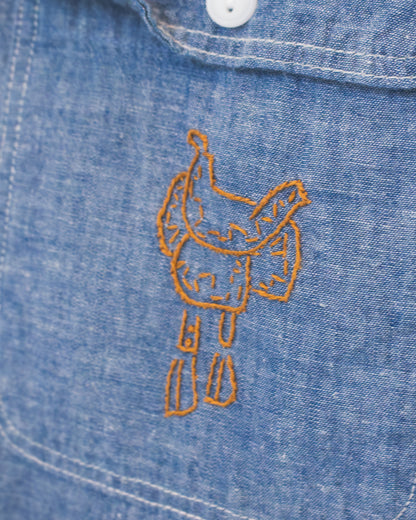 Close-up of a blue denim pocket with embroidered saddle.