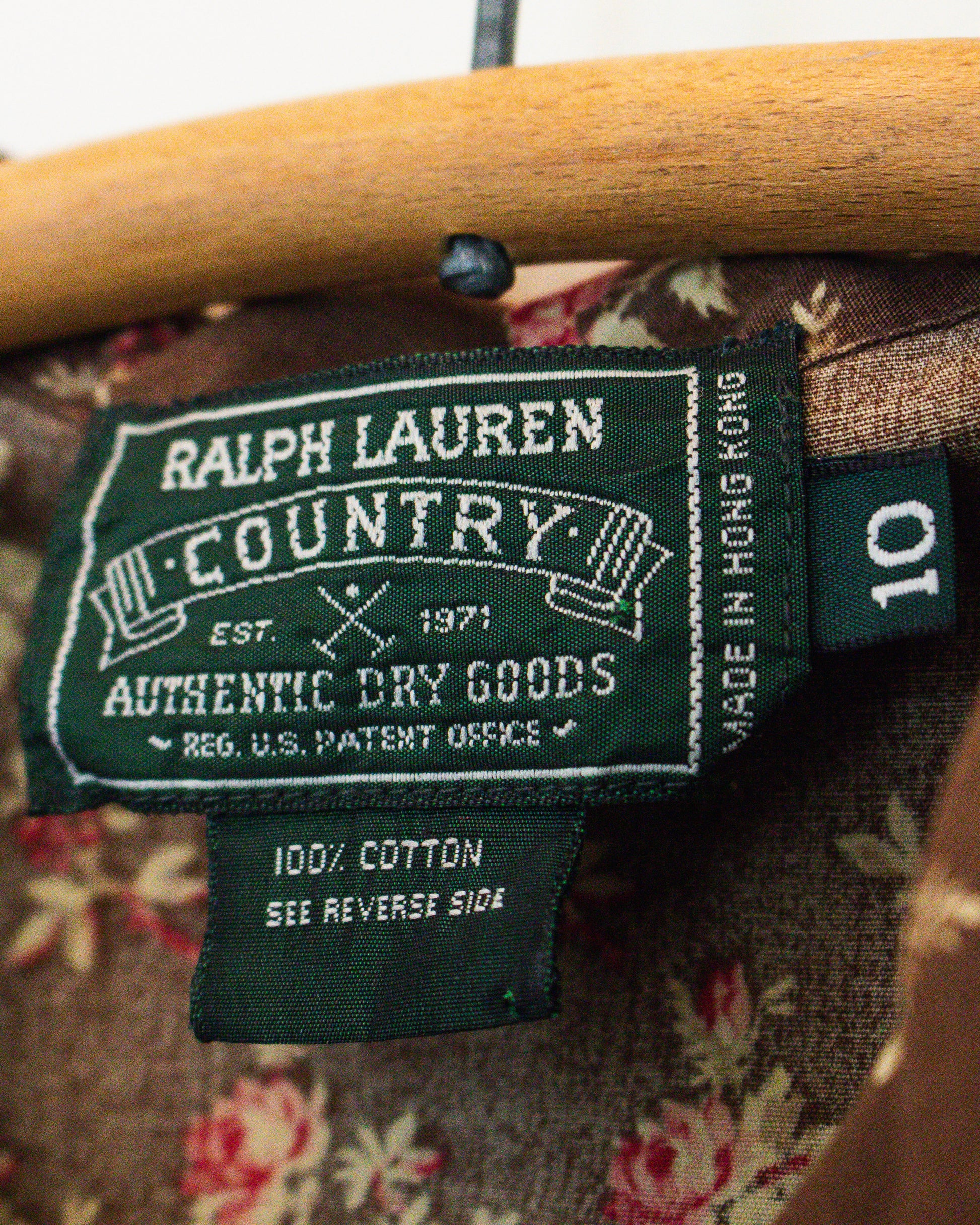 Close-up of a Ralph Lauren Country garment label on a floral-patterned garment, showing the brand name, 'Authentic Dry Goods,' and a size tag marked 10, as well as 100% Cotton.