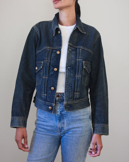 Woman wearing denim jacket with brass buttons with light blue jeans and white t-shirt.