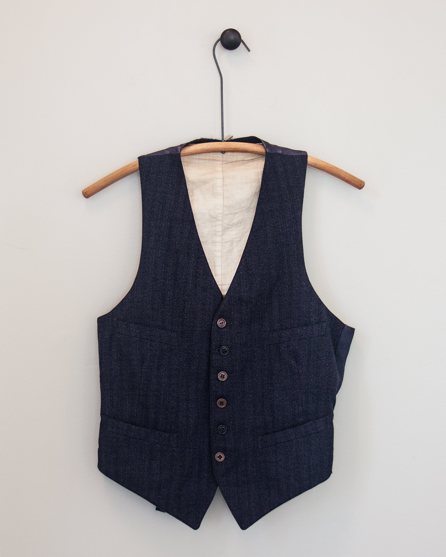 Navy and burgundy striped vest on hanger with white background.