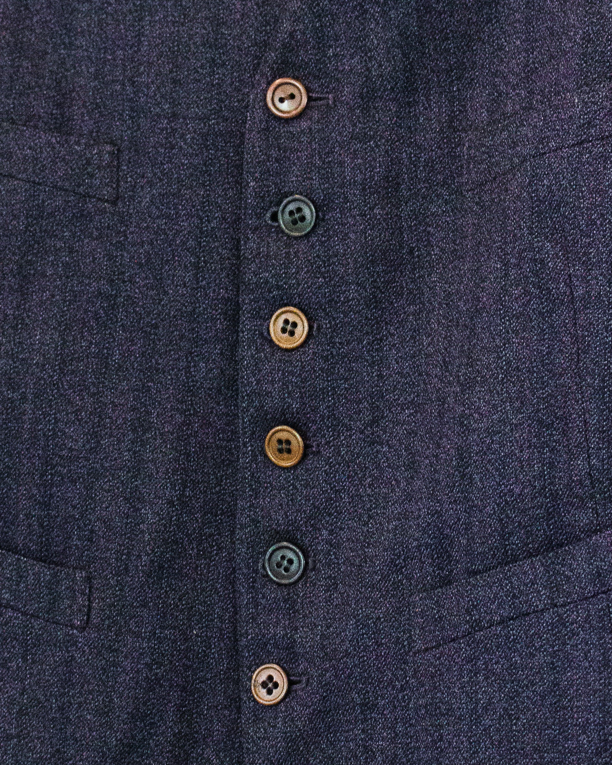 Close-up of a dark navy textured fabric garment with a vertical row of decorative buttons in muted brown and black tones.