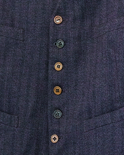 Close-up of a dark navy textured fabric garment with a vertical row of decorative buttons in muted brown and black tones.