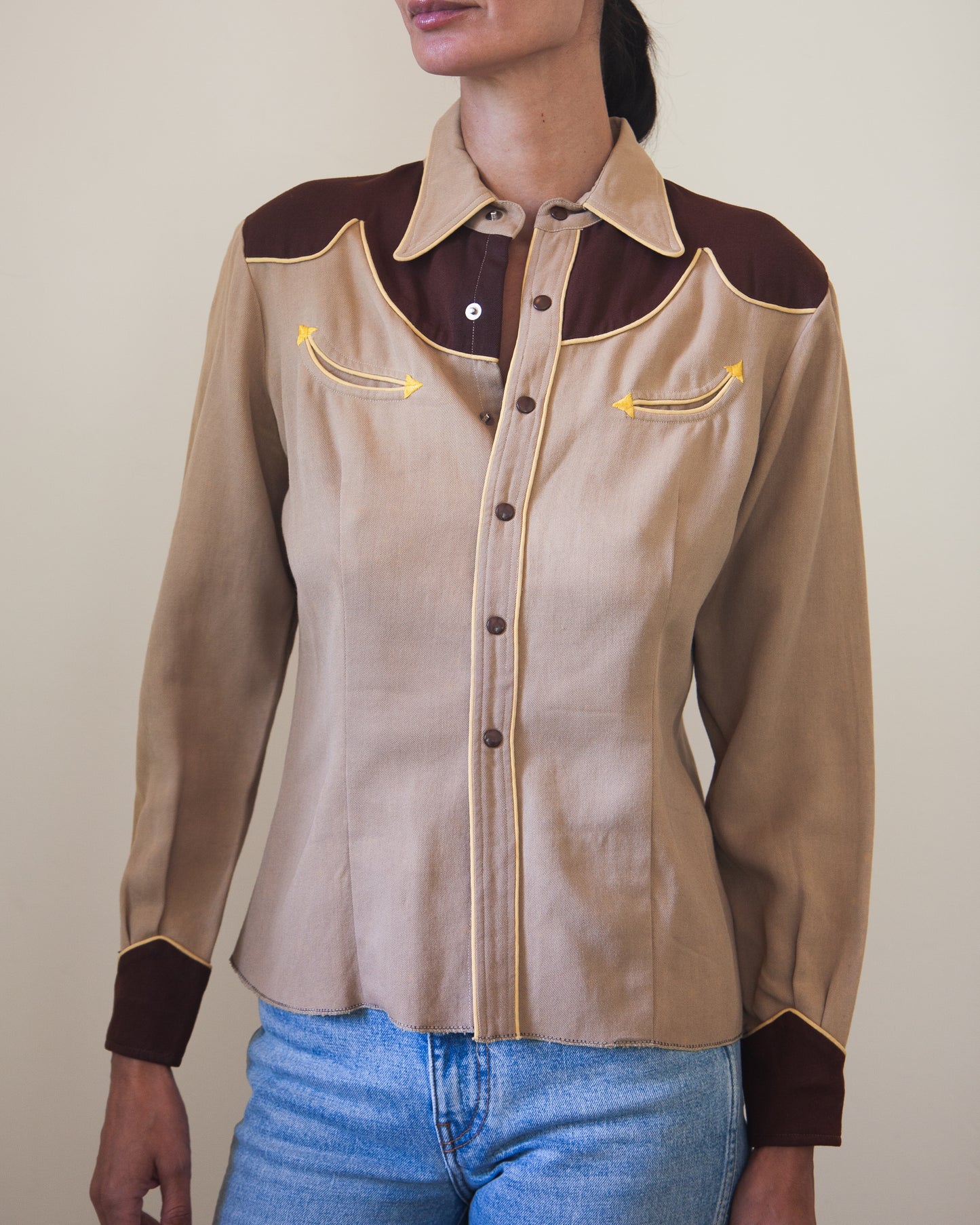 Woman wearing tan and brown Western shirt with smile pockets