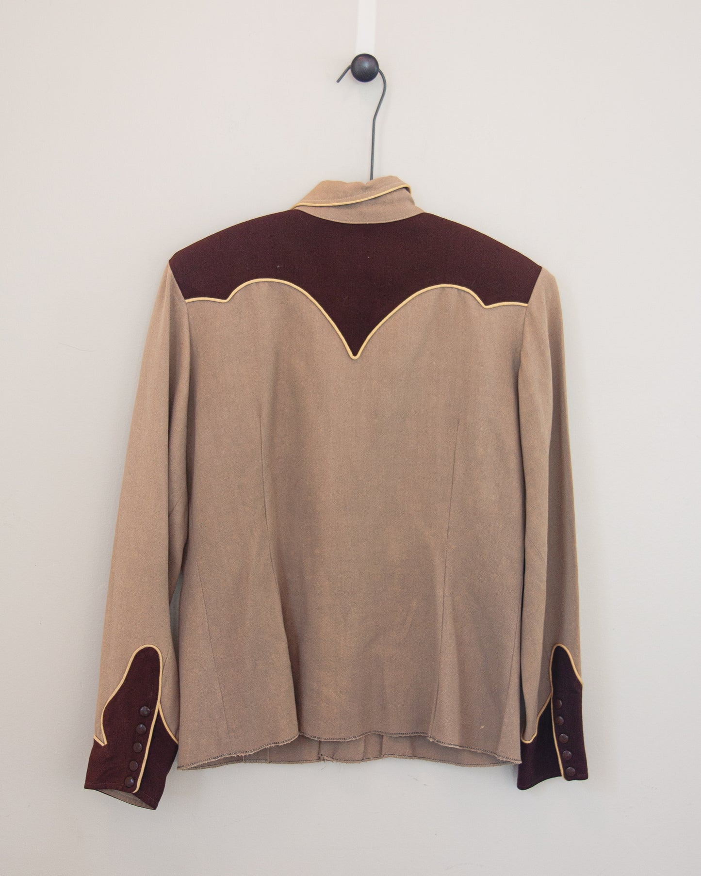Back of tan and brown Western shirt with smile pockets on a hanger