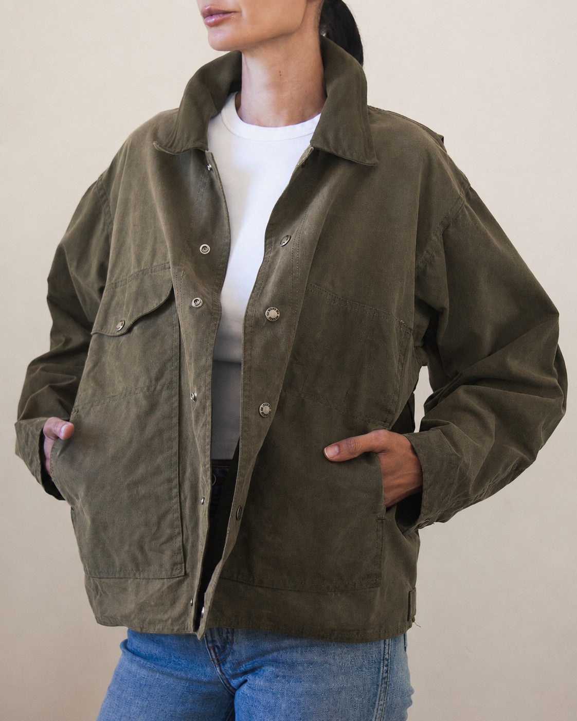 Woman wearing oversized olive green jacket with hands in pockets