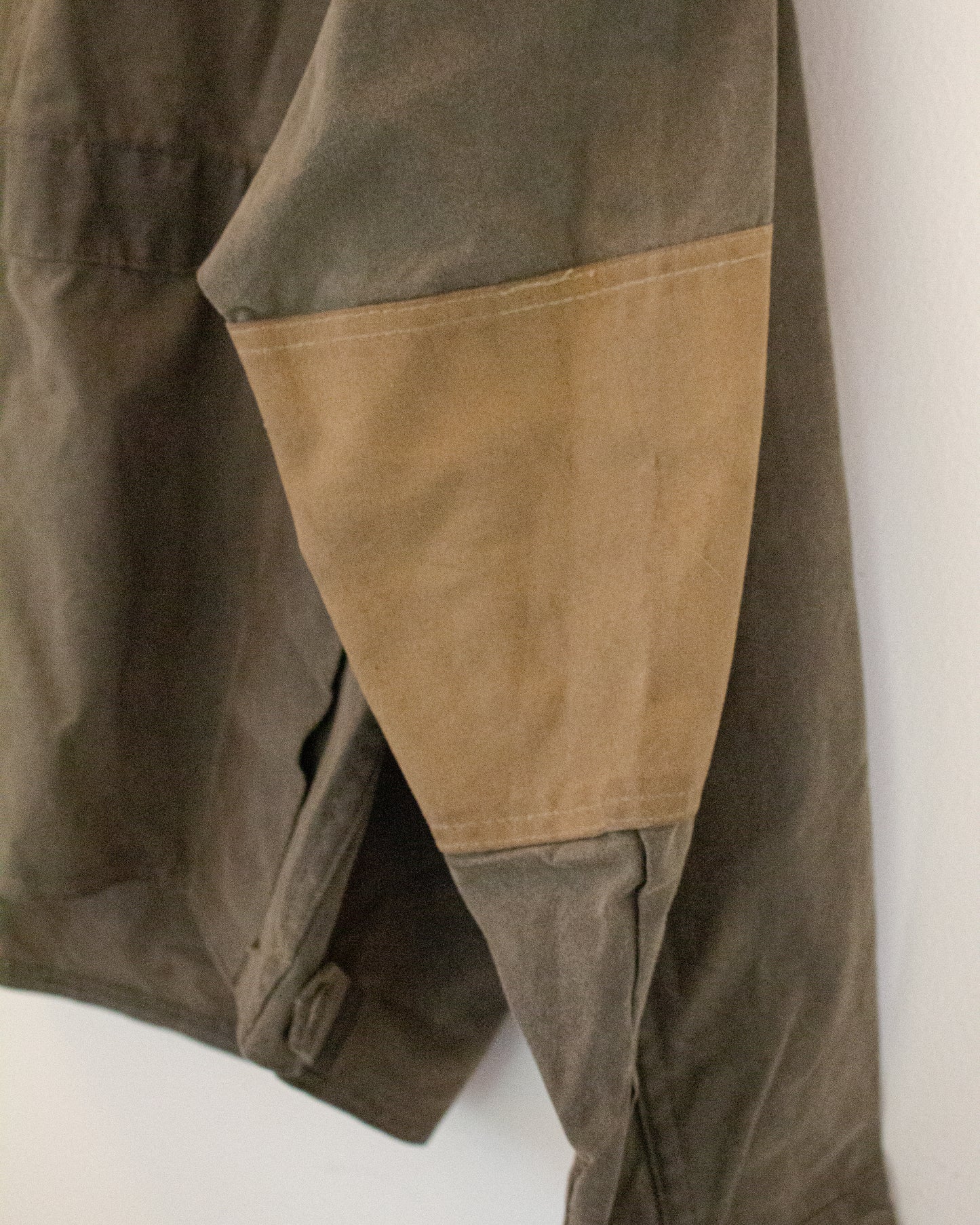 Close up of tan elbow patch on olive green jacket