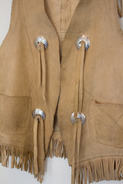 Close up view of front of suede leather vest with silver buttons and tassels