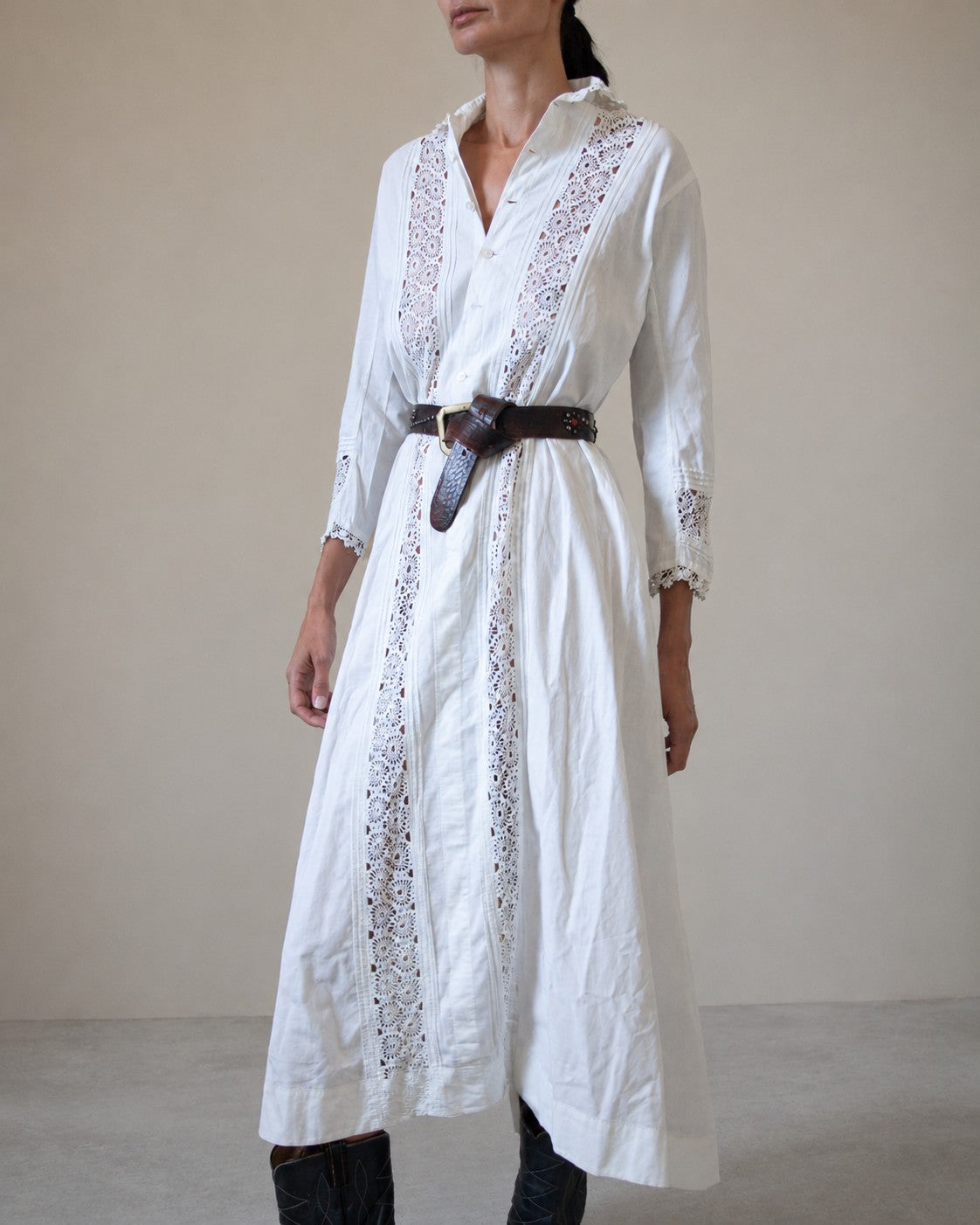 Woman wearing white dress with lace detailing and brown belt