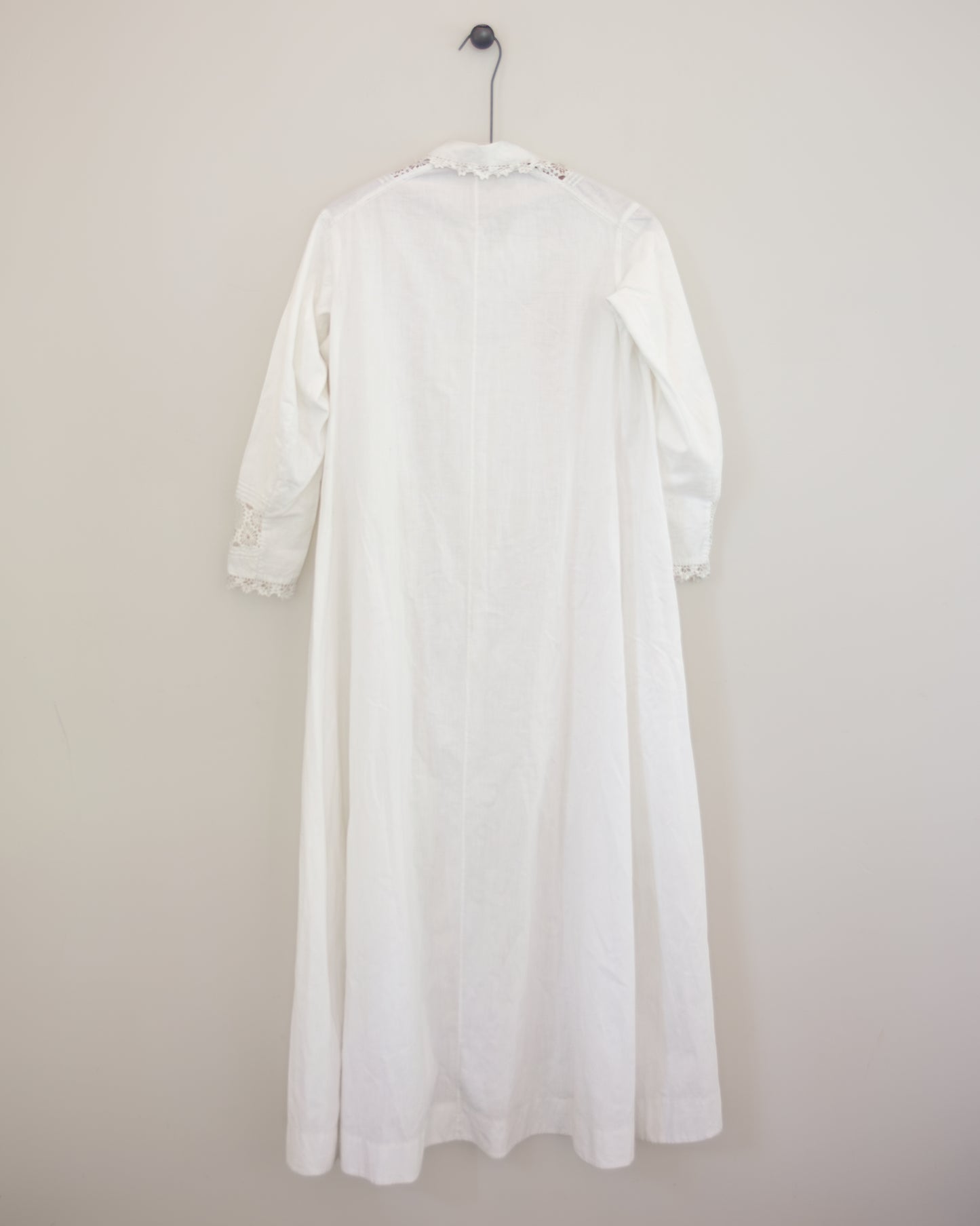Back of white dress with lace detailing on hanger