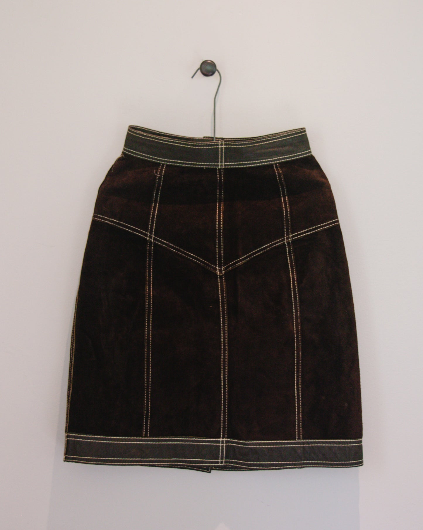 Back view of brown leather skirt on hanger 
