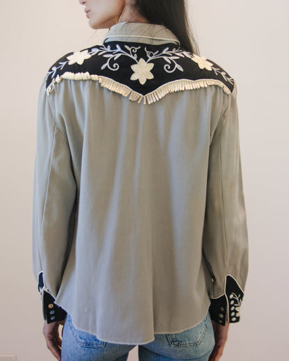 Light gray shirt with black and white embroidery on a plain background