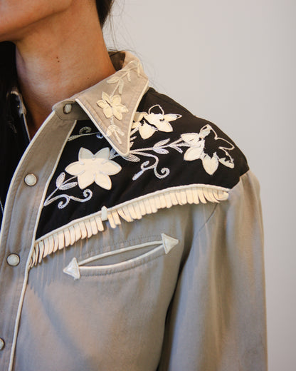 Close-up of a shirt with floral embroidery on a plain background