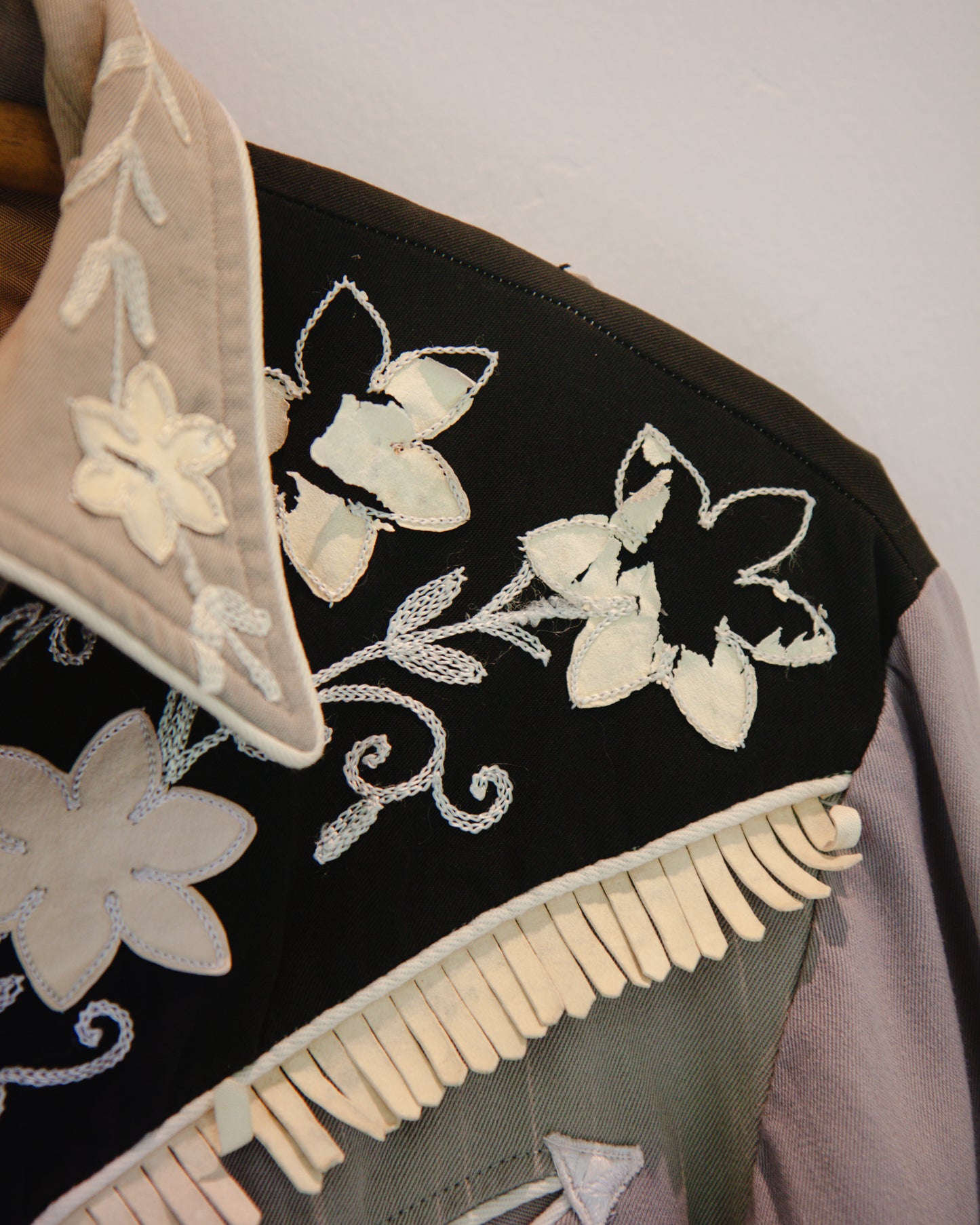 Embroidered black fabric with white floral patterns and fringe details.