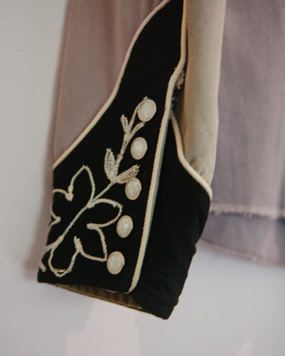 Black embroidered shirt with white floral patterns on a neutral background