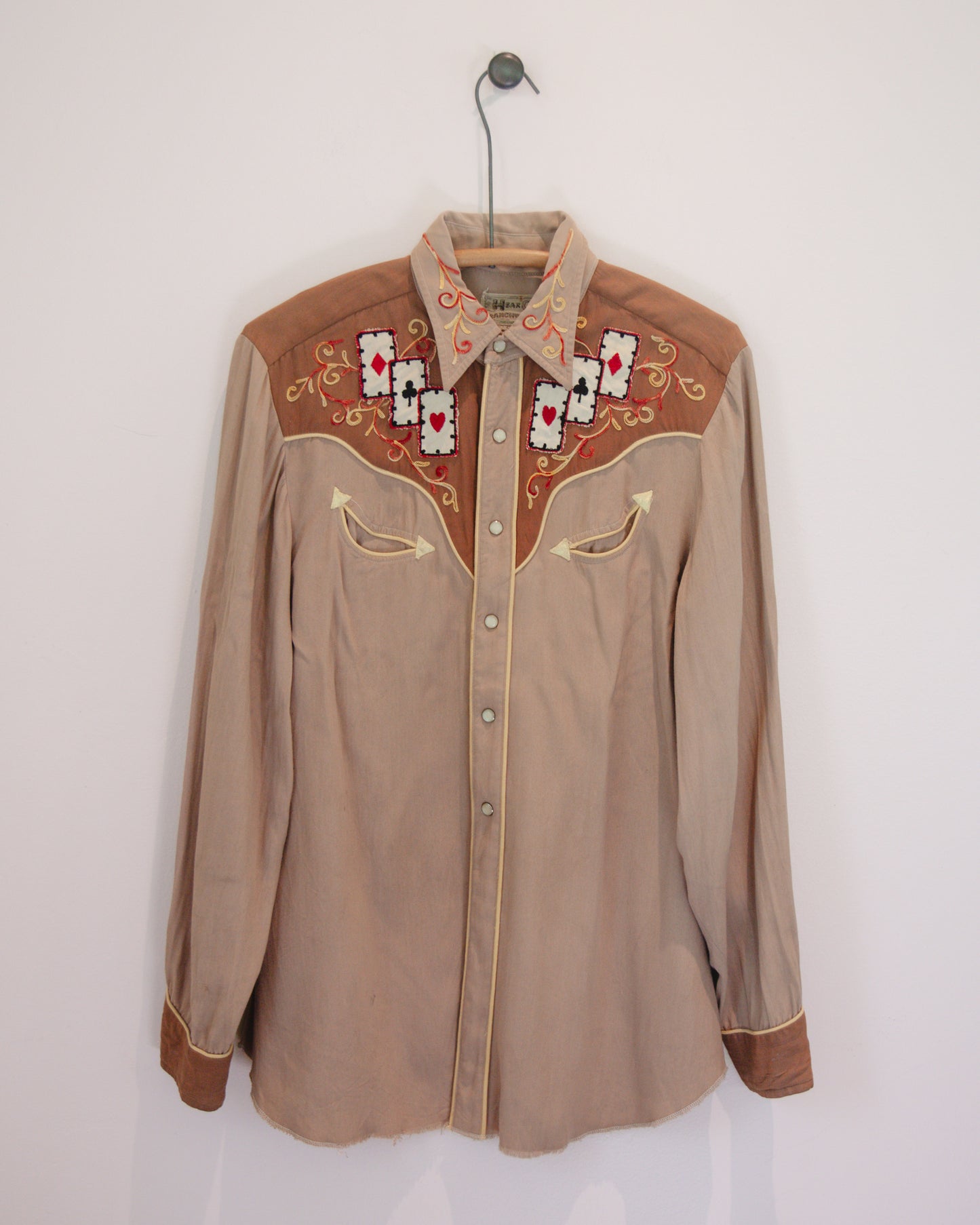 Brown embroidered shirt on a hanger against a white background