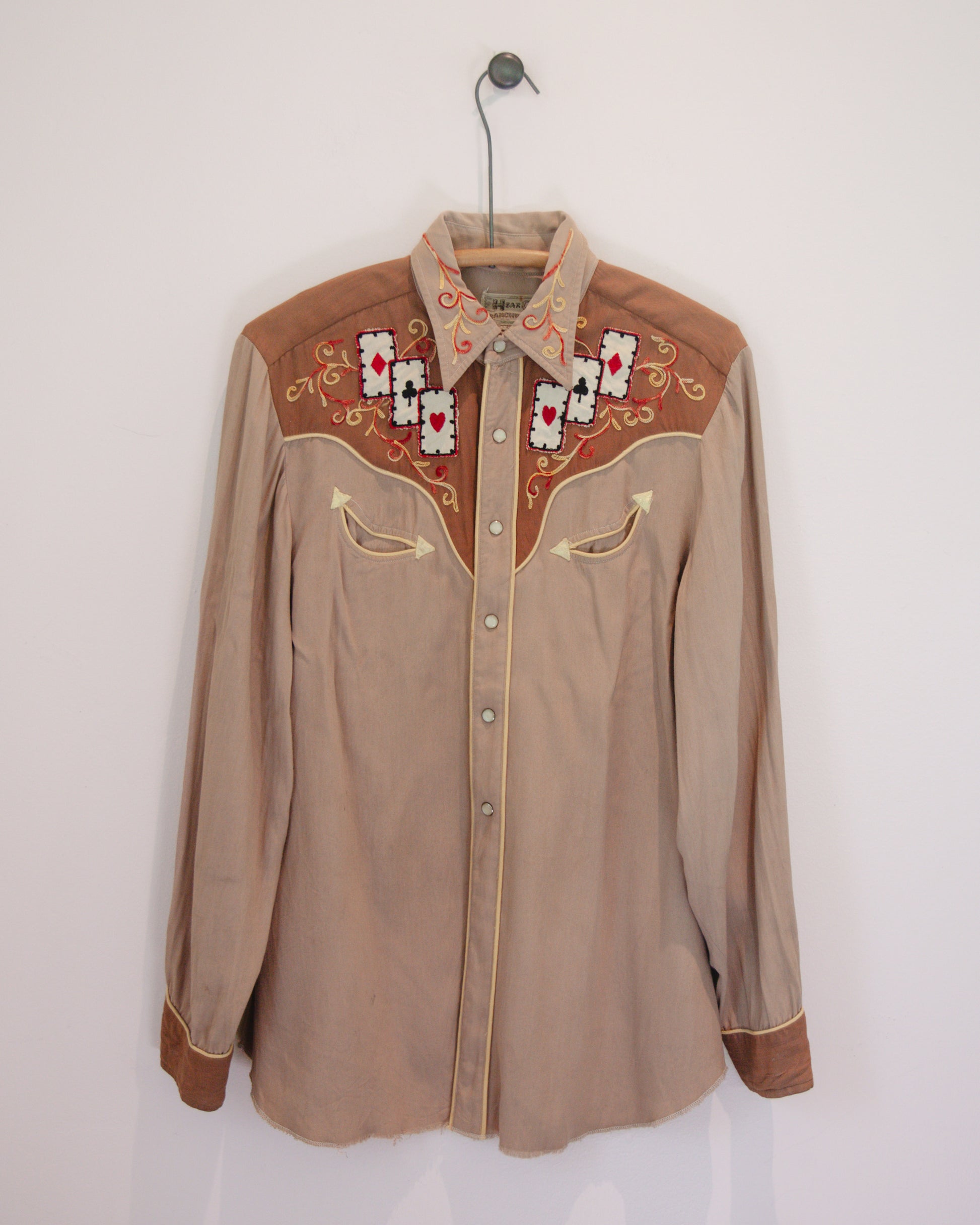 Brown embroidered shirt on a hanger against a white background