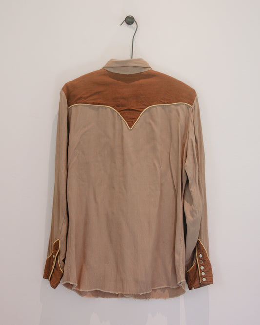 Brown and beige long-sleeve shirt on a hanger against a white wall