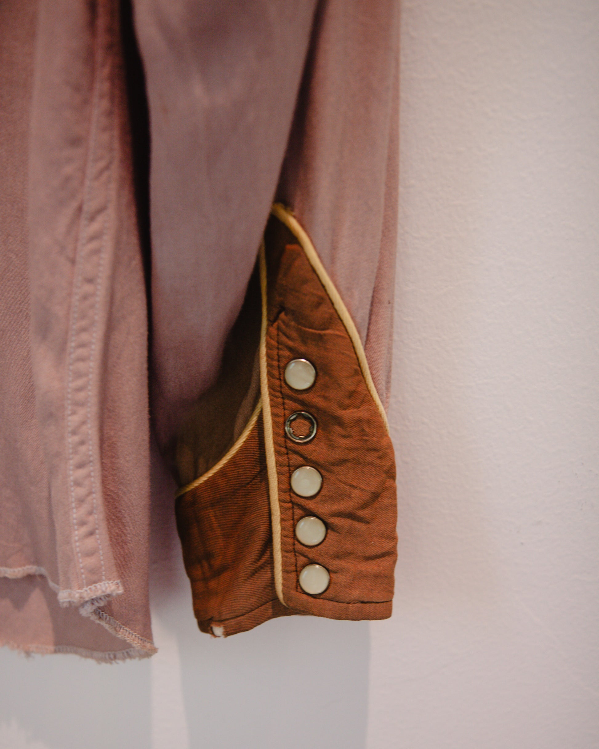 Close-up of a brown garment with button details on a light background