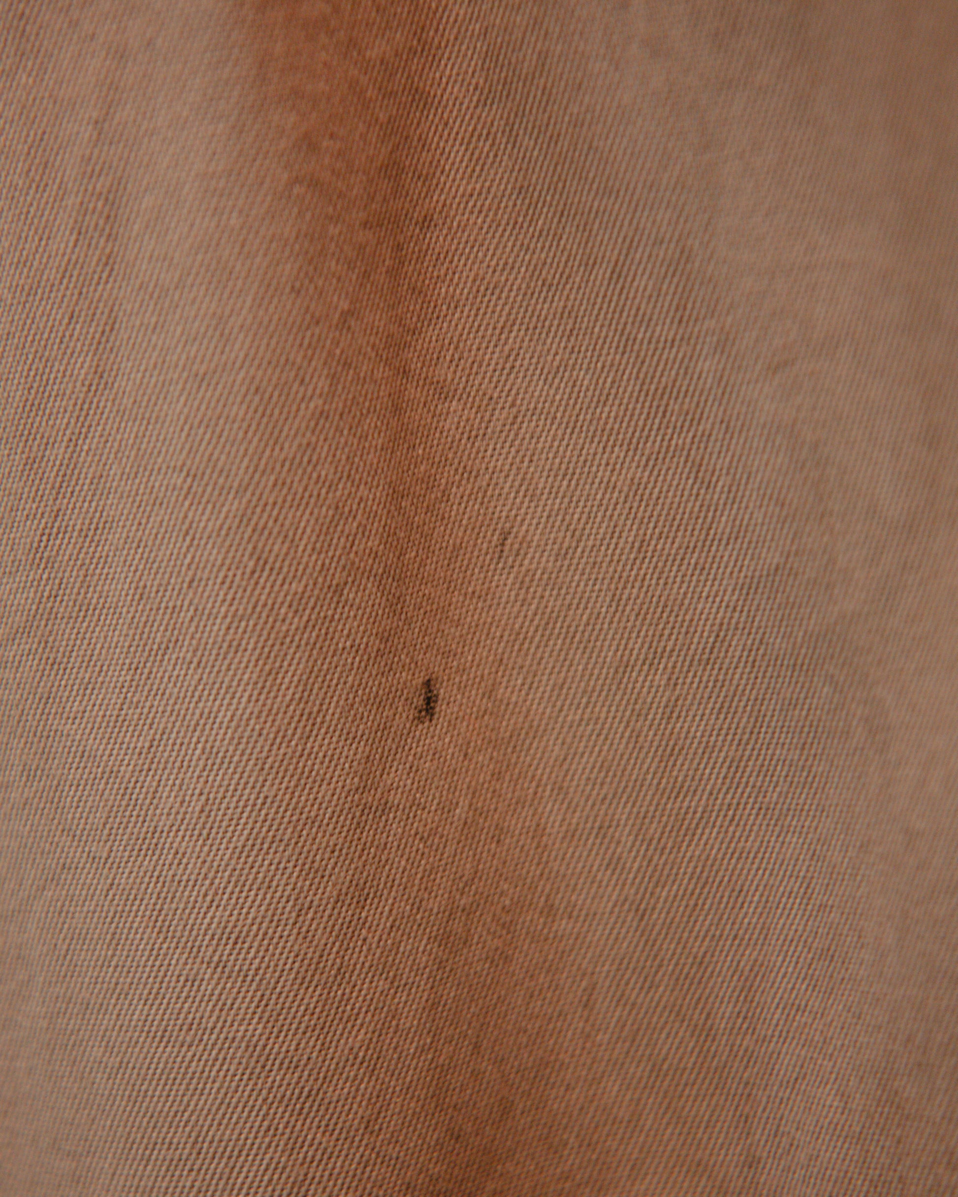 Close-up of brown fabric texture with a small dark spot